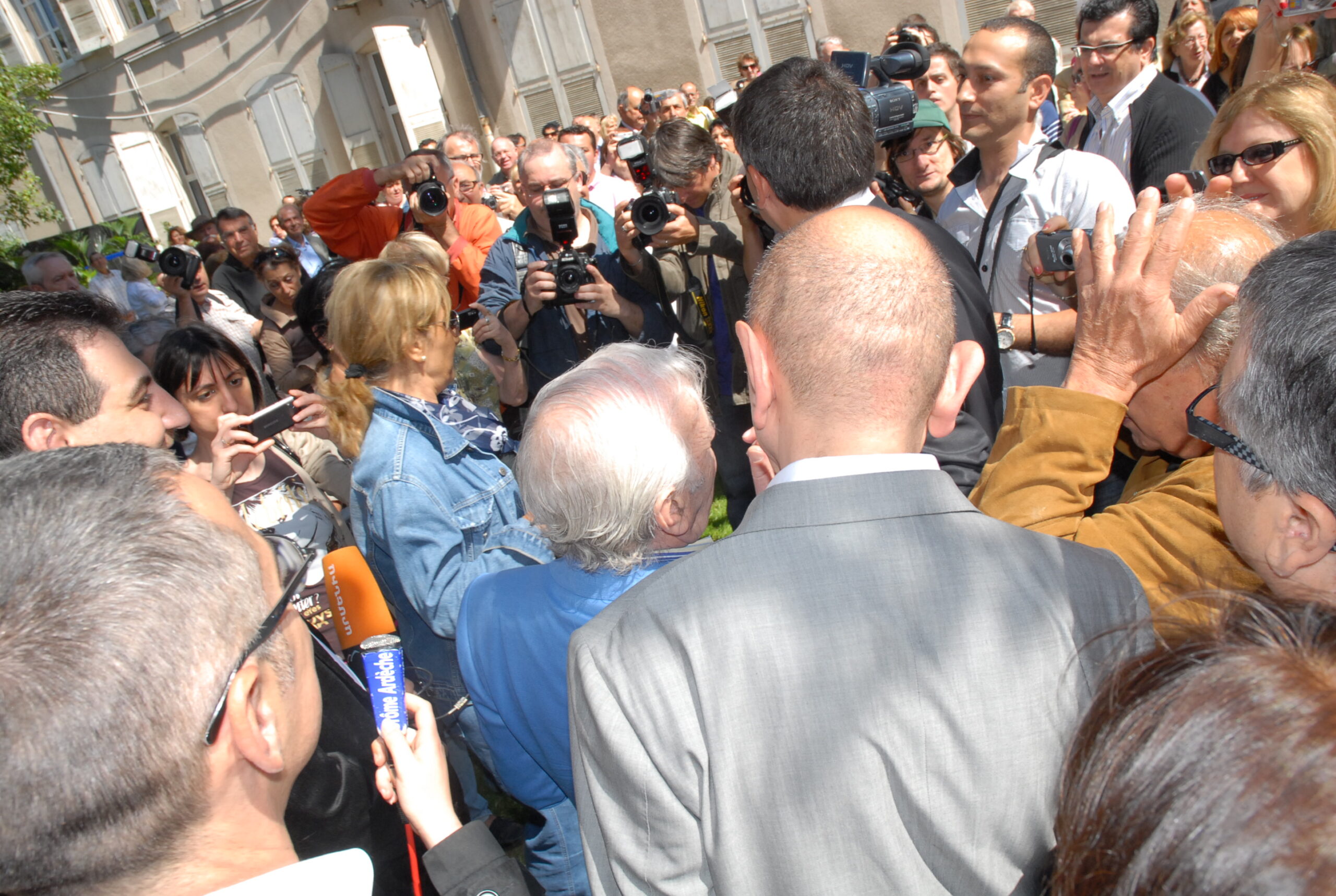 Charles Aznavour entouré de photographes